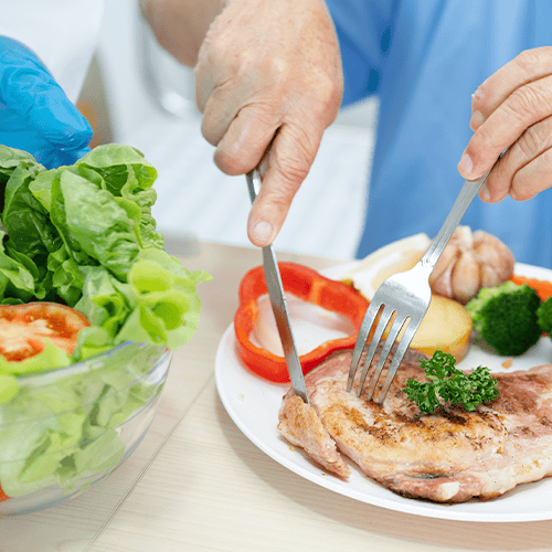 Pessoa realizando refeição saudável com proteína, salada e legumes, representando alimentação após cirurgia da vesícula.
