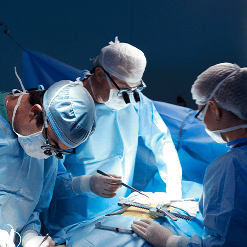 Equipe médica realizando procedimento cirúrgico em centro cirúrgico, com profissionais paramentados e foco na operação.